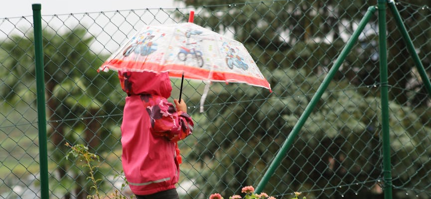girl in jacket and with umbrella in garden